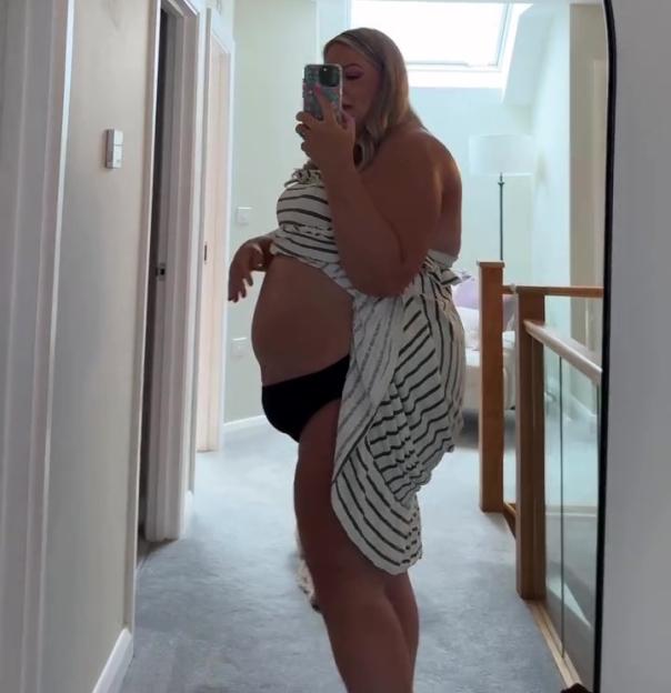Pregnant person taking a selfie in a mirror.