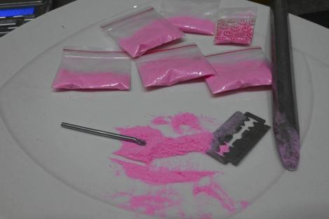 Pink cocaine in baggies on a plate with razor blade and other drug paraphernalia.