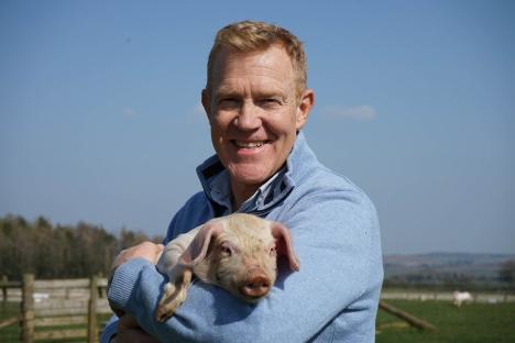 Adam Henson holding a piglet.
