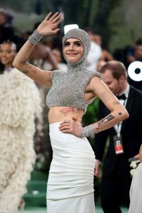 Cara Delevingne at the Met Gala in a jeweled top and white skirt.