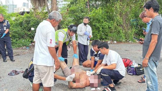A man receiving medical attention on the ground, surrounded by several people.