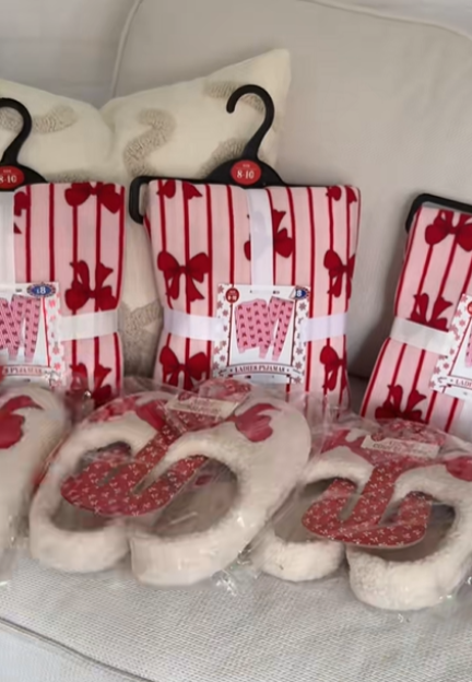 Pink and white striped pajamas with red bows, and white slippers with red patterns on a white couch.