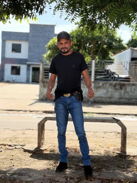 Reinaldo da Silva Melo, arrested for murder, stands outdoors with his thumbs up.