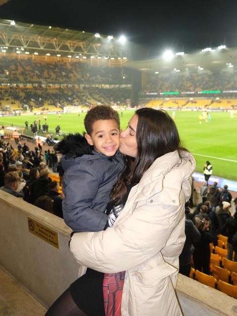 Woman kissing child in stadium stands.