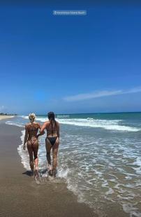 Two women walking on a beach.