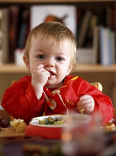 Toddler eating food in a high chair.