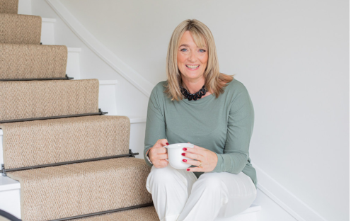Woman sitting on stairs holding a coffee cup.