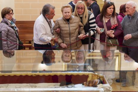People viewing the remains of Saint Teresa of Jesus in a glass case.