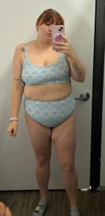Woman in a patterned bikini taking a selfie in a changing room.