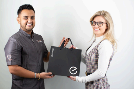 Two people exchanging a black Enlighten gift bag.