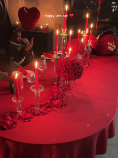 Romantic Valentine's Day dinner table setting with candles, roses, and rose petals.