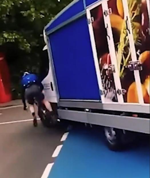 A cyclist on the ground next to a bicycle after being hit by a white delivery van.