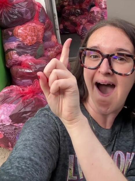 Woman pointing at bags of clothing she bought at a charity shop and resold for £300.