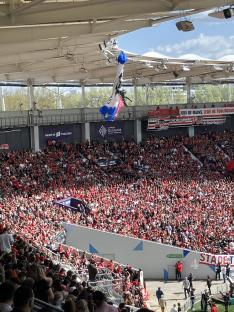 A skydiver descends into a crowded stadium.