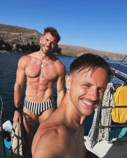 Two men in swimsuits on a boat.