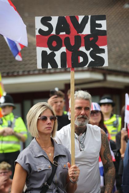 Protestor holding a sign that says "Save Our Kids" at a demonstration.