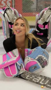 a woman wearing a pair of pink and blue bauer hockey gloves