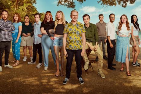 Cast photo of a reality show, outdoors on a beach.