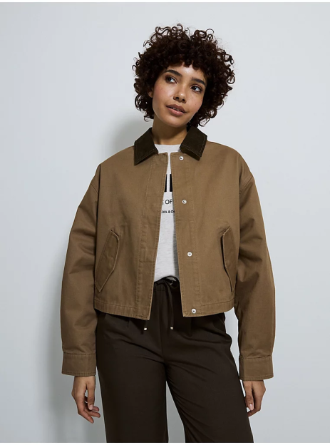Woman wearing a brown cropped jacket with a dark collar.