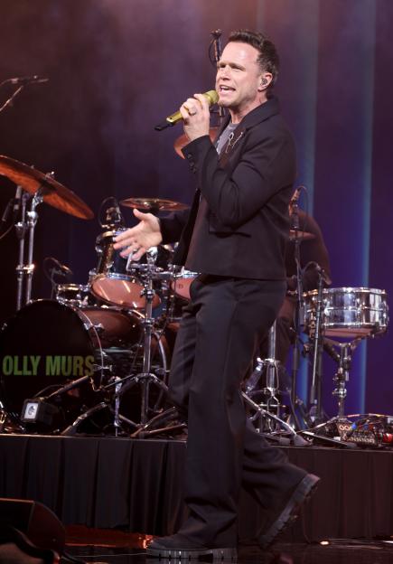 Olly Murs performing onstage with a golden microphone at The Music Industry Trust Awards.