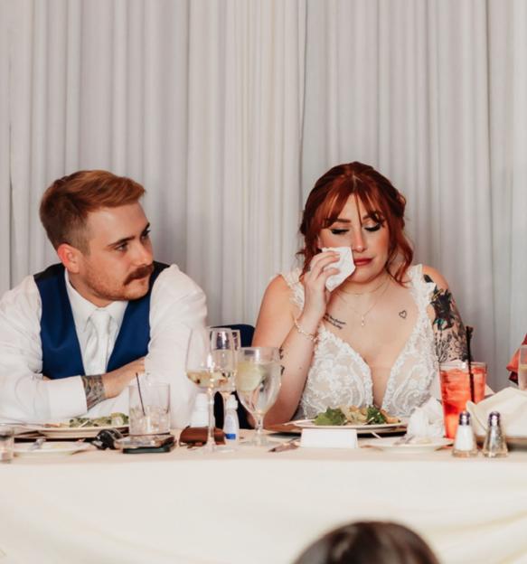 A bride wipes away tears at her wedding reception.