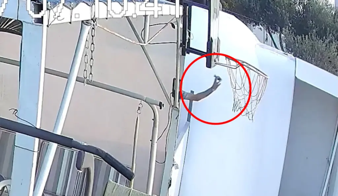 Security camera footage of a man throwing a grenade into a basketball hoop.