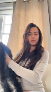 Woman holding a small dark dog.