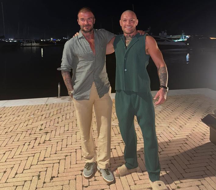 Conor McGregor and David Beckham posing together at night.
