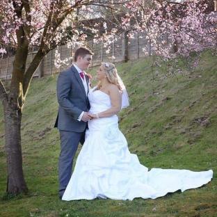 Bride and groom posing for a wedding photo under a blossoming tree.
