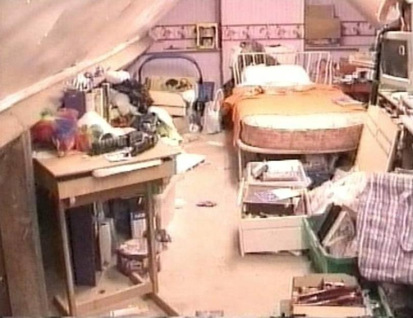 a messy bedroom with a bed , desk , and television .