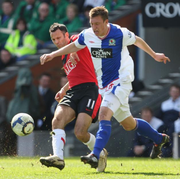Ryan Giggs of Manchester United clashes with a Blackburn Rovers player during a soccer match.