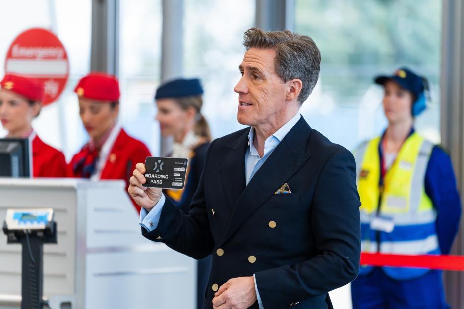 Man in suit holding boarding pass at airport.