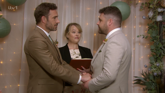 Two men holding hands during a wedding ceremony.