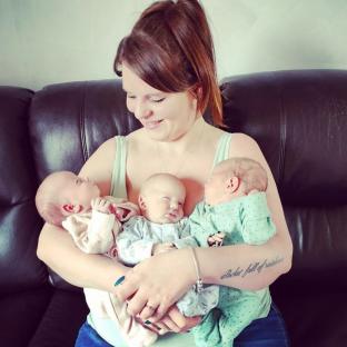 Mother holding her newborn triplets.