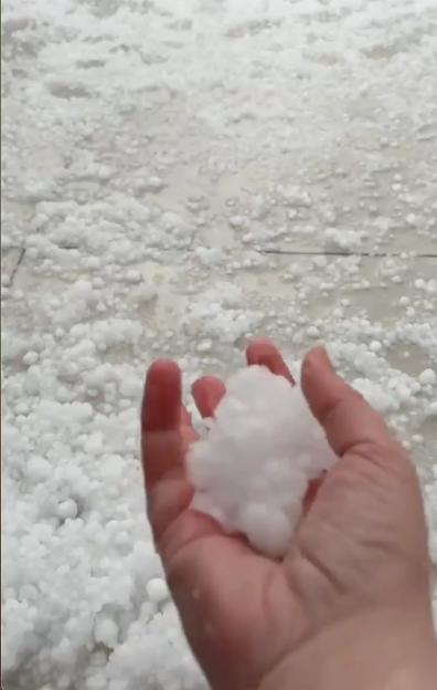 Hailstones covering the ground, with a hand holding some.