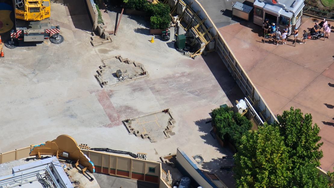 Aerial view of a construction site with removed structures, a crane, and people near a food stand.