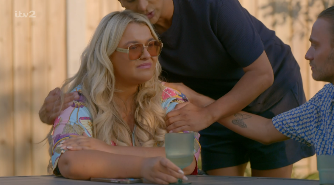 Screenshot of a woman being comforted by two people.