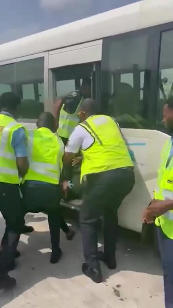 People in yellow safety vests helping someone off a bus.