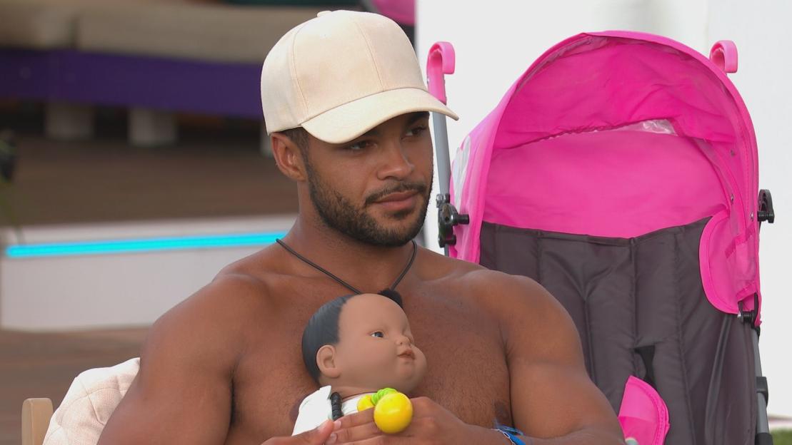 Jamie Allen from Love Island holding a baby doll.