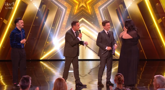 Screenshot of four people on a stage with a gold star backdrop.