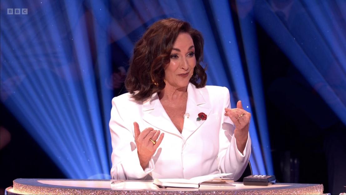 Shirley Ballas on Strictly Come Dancing, wearing a white blazer and a red poppy pin.