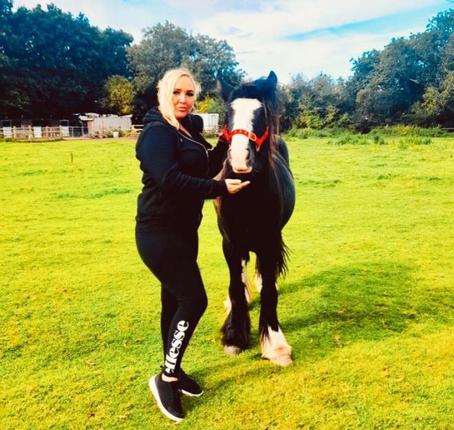A woman standing next to a horse wearing Ellesse leggings