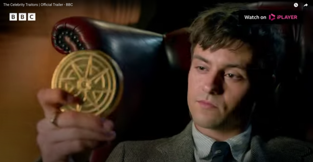 A person holding a circular gold coin with an intricate design.