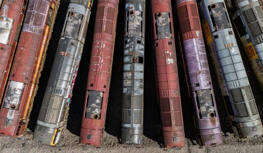 Aerial view of a dozen rusty diesel locomotives abandoned in a quarry.