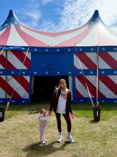 Woman and toddler standing in front of a circus tent.