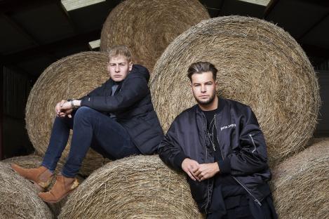 Two men sitting on hay bales.