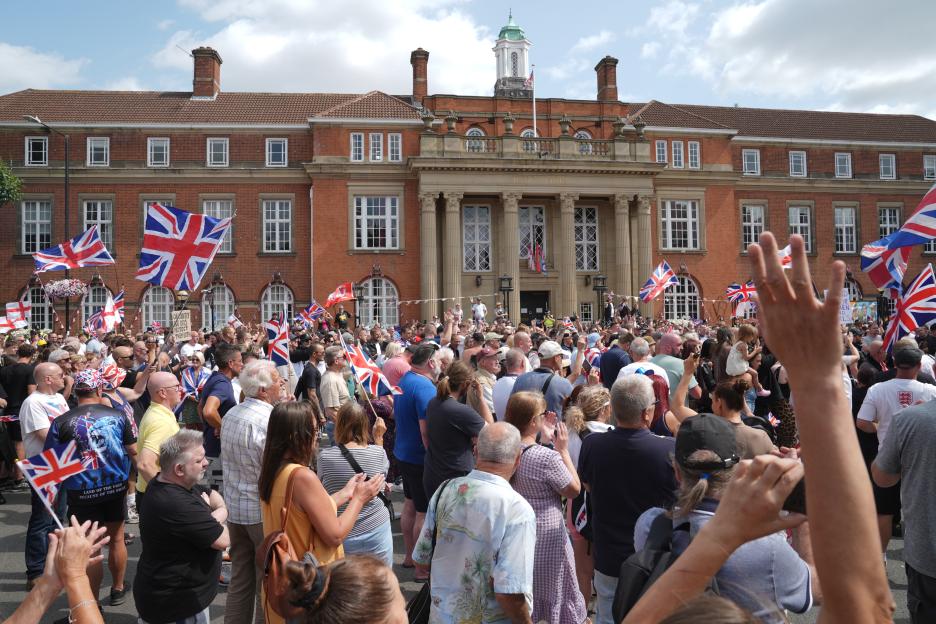 Anti-immigration protesters march through Nuneaton, UK, waving Union Jack flags.
