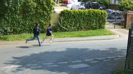 Two people running across a road.