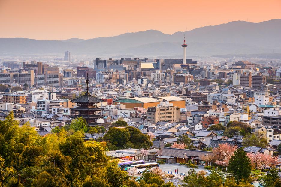 Kyoto, Japan city skyline at dusk with mountains in the background.