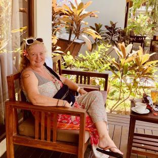 Woman sitting on a patio, enjoying a drink.